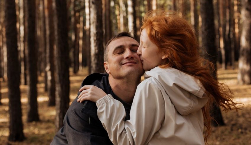 A man and woman kissing in a forest.