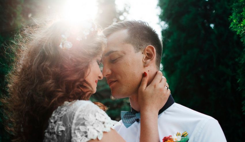 A bride and groom embracing in the sun.