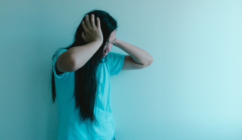 A woman with long hair covering her head with her hands.