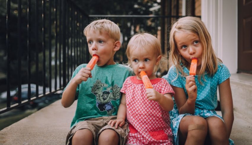 Three children sitting on steps and eating oranges.