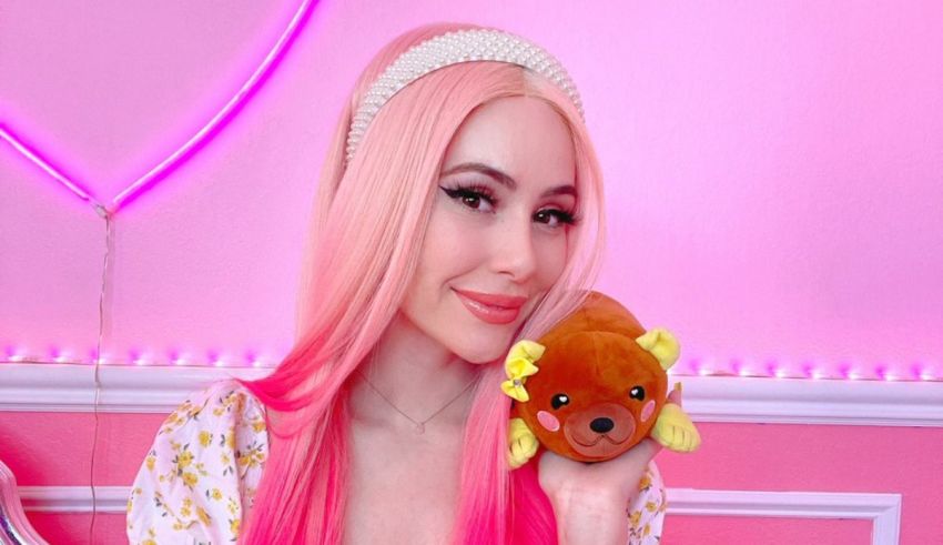 A girl with pink hair holding a pink teddy bear.