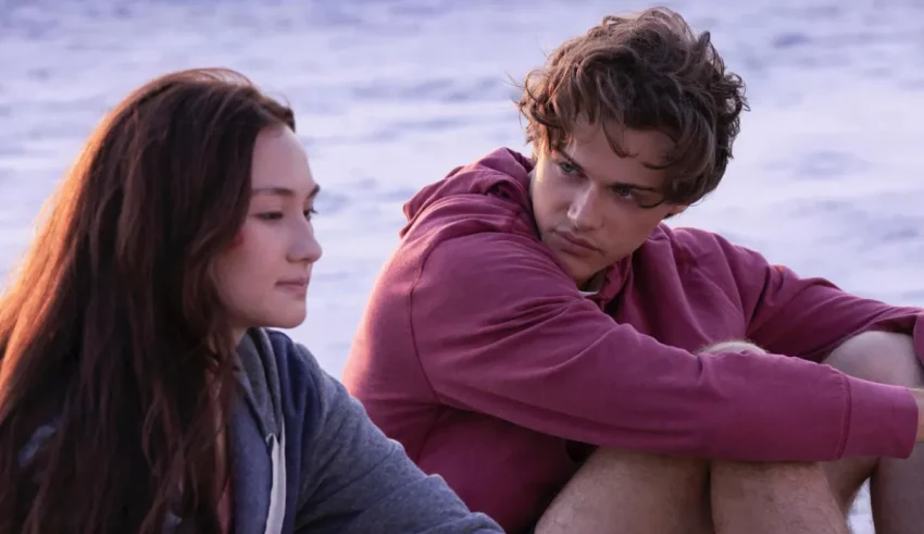 A young man and woman sitting on the beach.