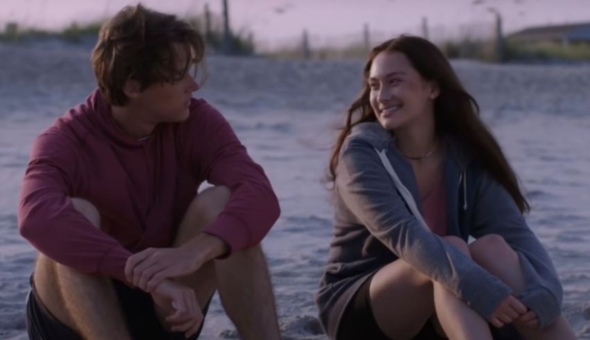 A young man and woman sitting on the beach.