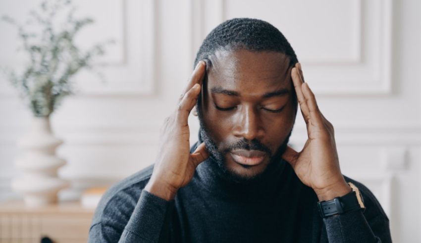 A black man with his hands on his head.