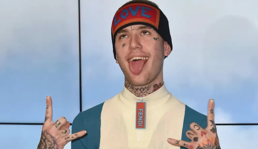 A man with tattoos and a beanie is making a gesture.