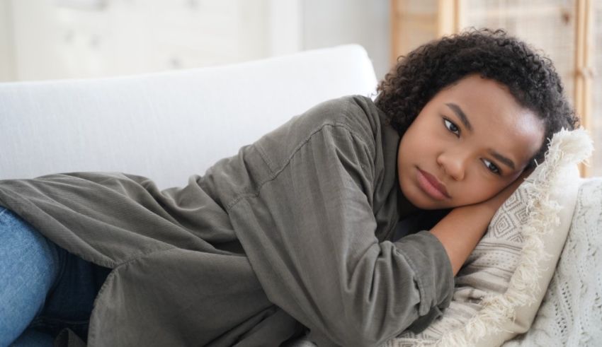 A young black woman laying on a couch with her head resting on her shoulder.