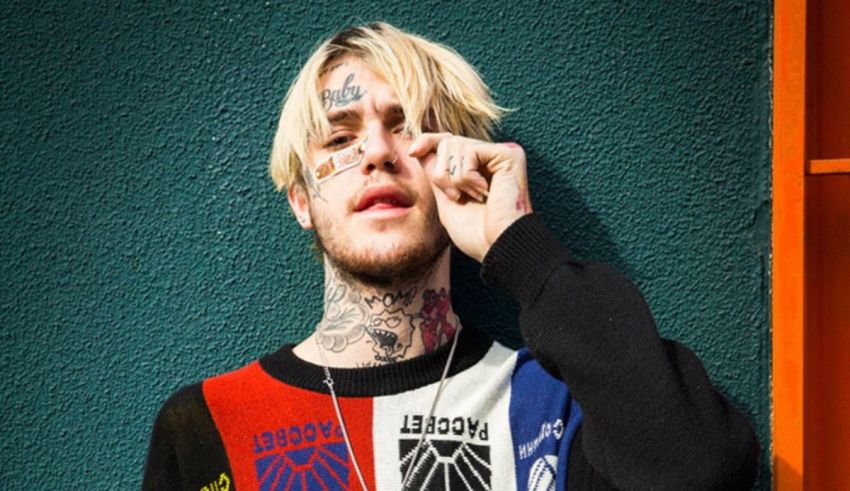 A man with tattoos leaning against a wall.