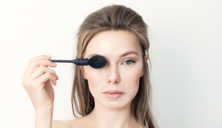 A woman is using a brush to apply makeup to her eye.