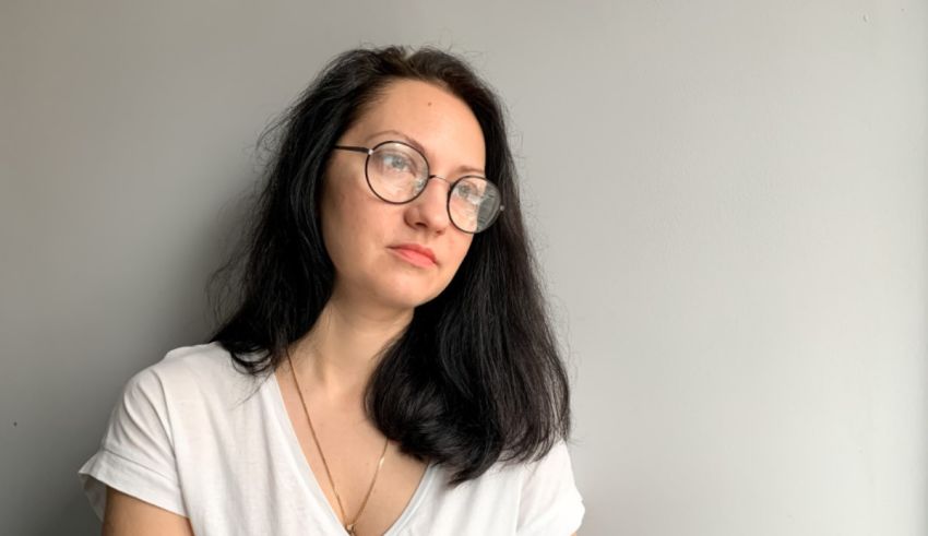 A young woman wearing glasses and a white t - shirt.