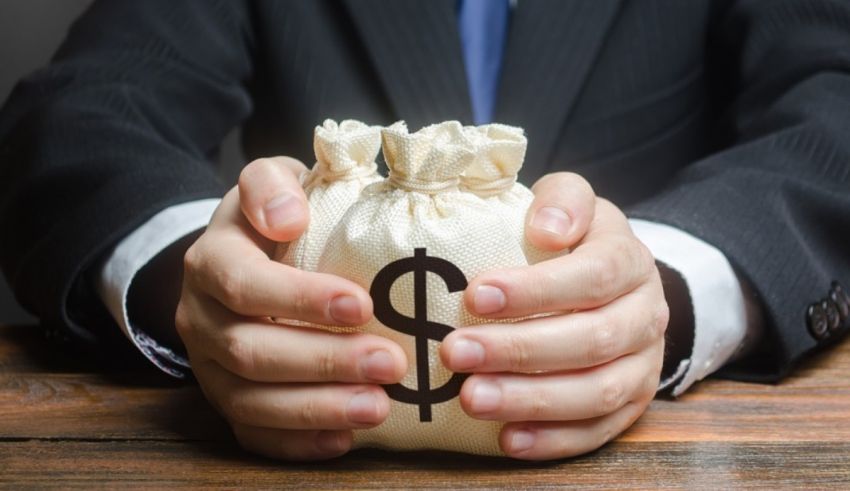 A businessman holding a money bag with a dollar sign on it.