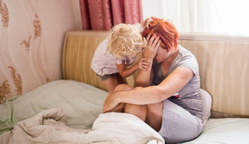 A woman with red hair and a little girl sitting on a bed.
