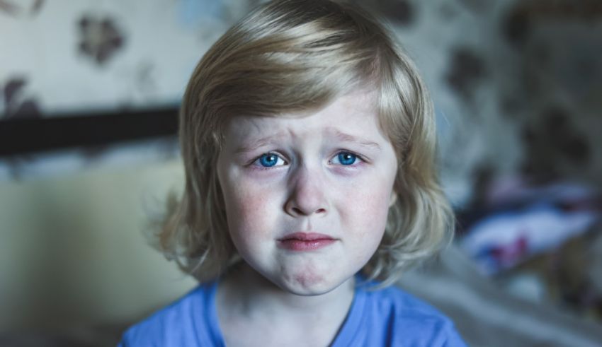 A young girl with blue eyes is sitting on a bed.