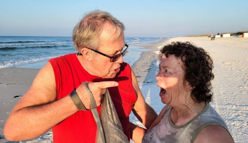 A man and woman on a beach talking to each other.