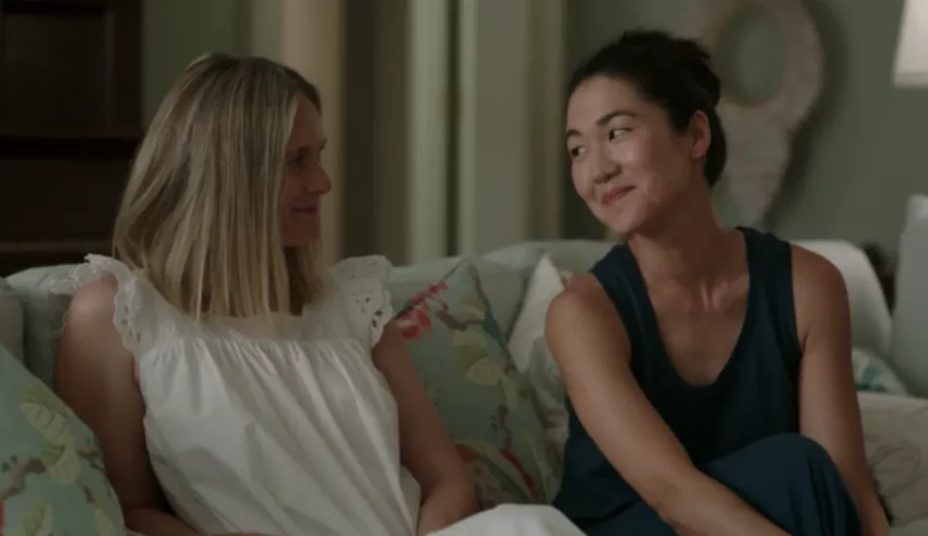 Two women sitting on a couch talking to each other.