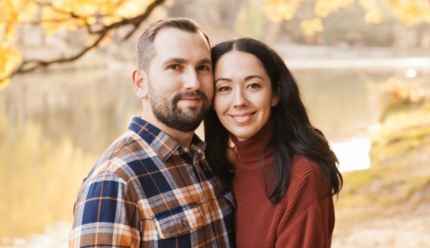 A couple posing in front of a lake during their engagement session.