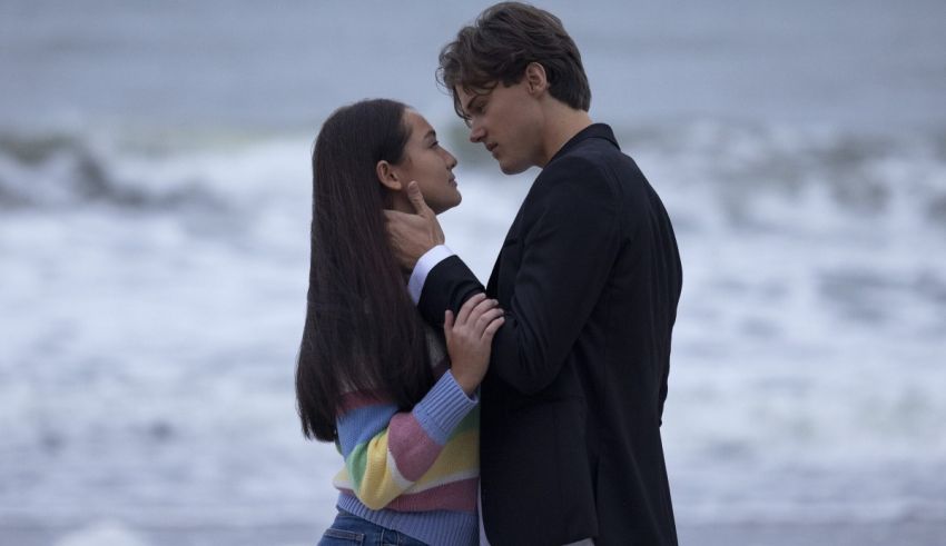 A man and woman kissing on the beach.