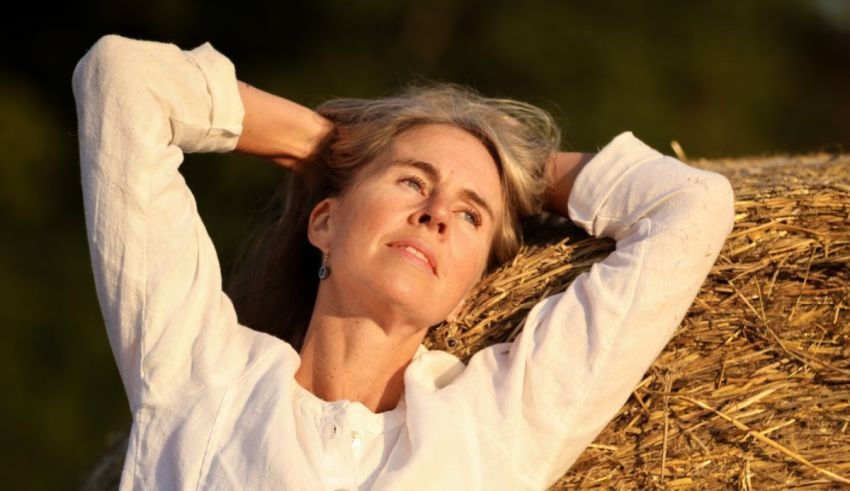A woman is laying on a hay bale.