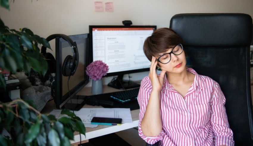 A woman sitting in front of a computer with her head in her hands.