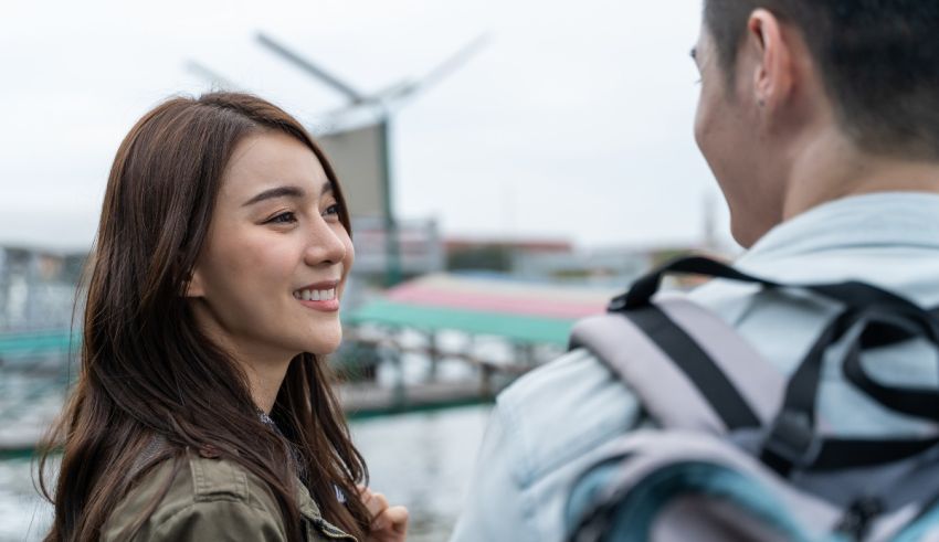 A man and woman are talking to each other in front of a windmill.
