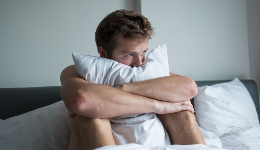 A man is sitting in bed with a pillow under his head.