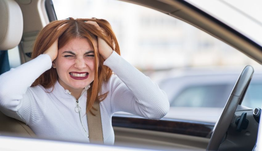 A woman in a car with her head in her hands.