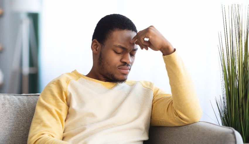 A man sitting on a couch with his head resting on his hand.