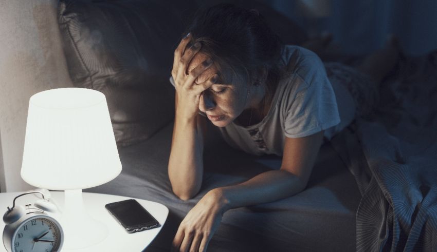 A woman laying in bed at night with an alarm clock.