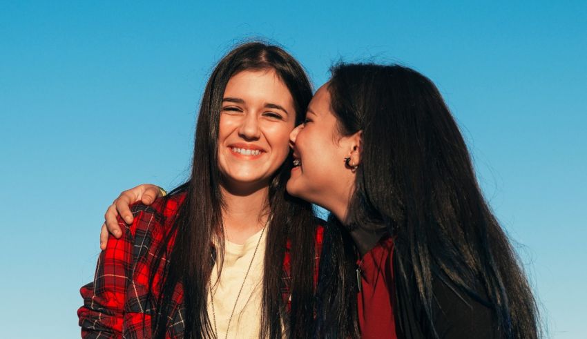 Two women hugging each other in front of a blue sky.