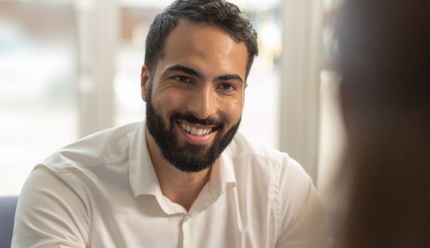 A man with a beard smiling at a woman in an office.