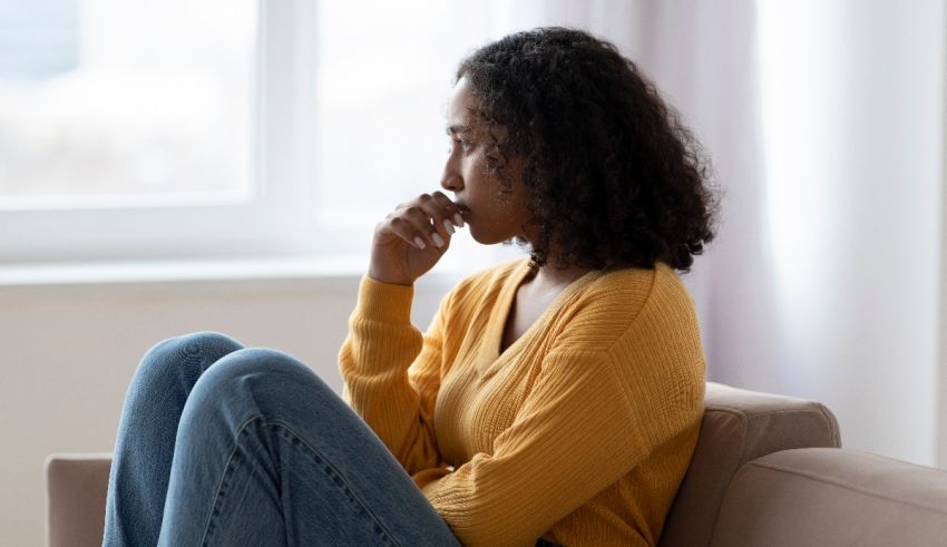 A woman sitting on a couch with her hand on her chin.