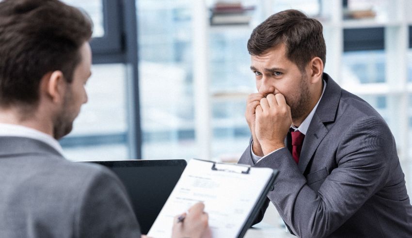 A man in a suit is talking to another man in an office.