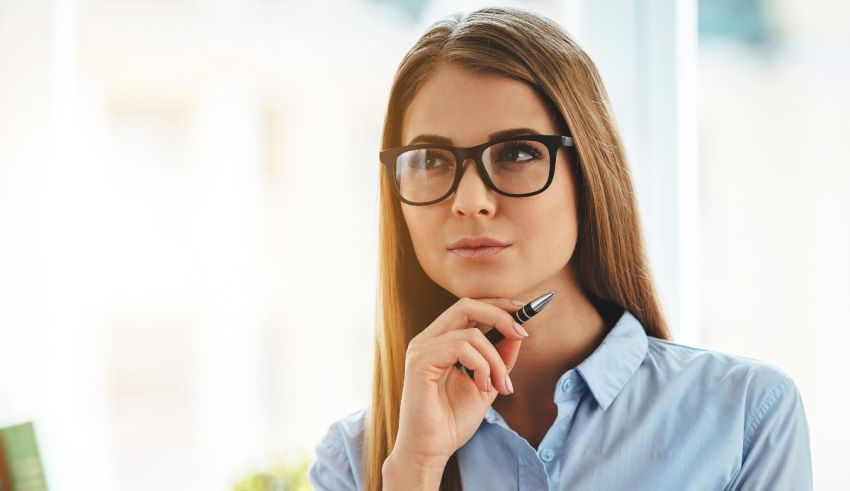 A woman in glasses is looking at her chin.
