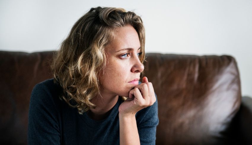 A woman sitting on a couch with her hand on her chin.