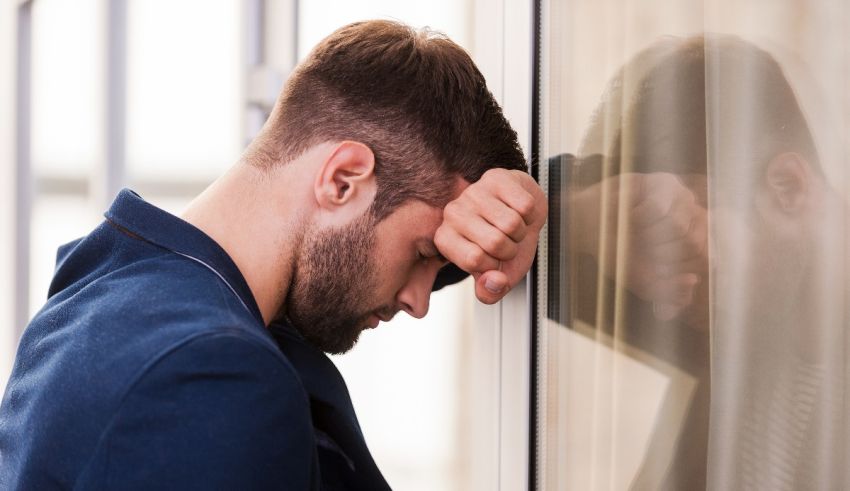 A man is leaning against a glass door.