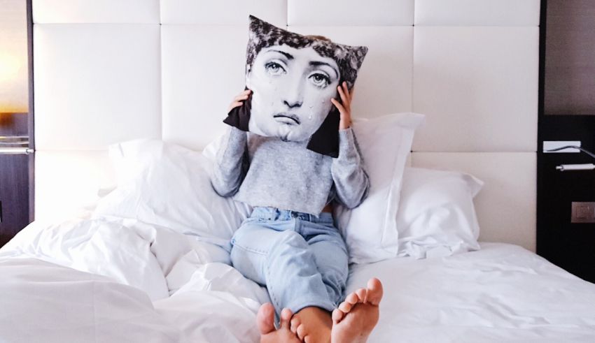 A woman laying on a bed with a pillow on her head.