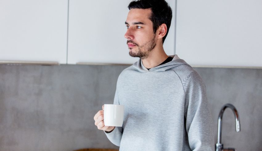 A man holding a cup of coffee in the kitchen.