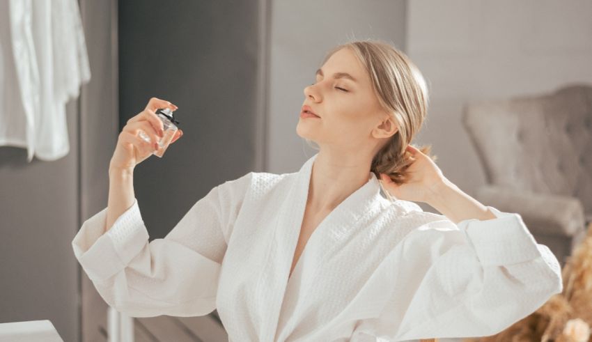 A woman in a white robe is holding a perfume bottle.