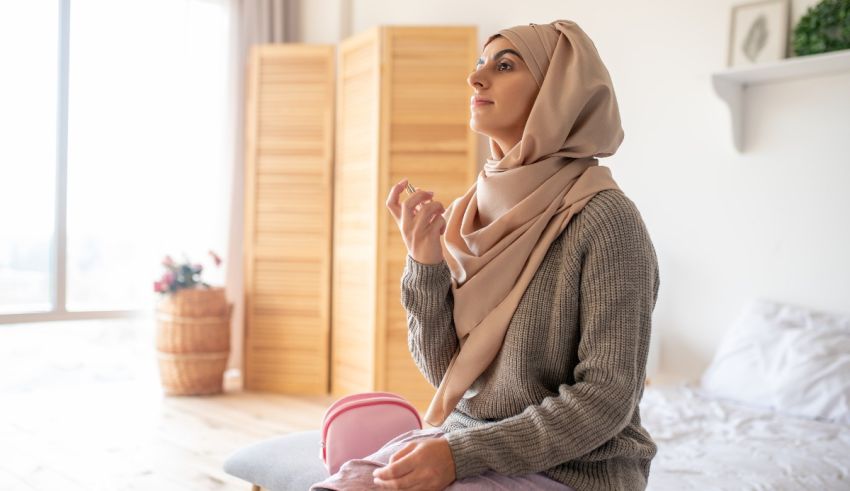 A muslim woman wearing a hijab sitting on a bed.