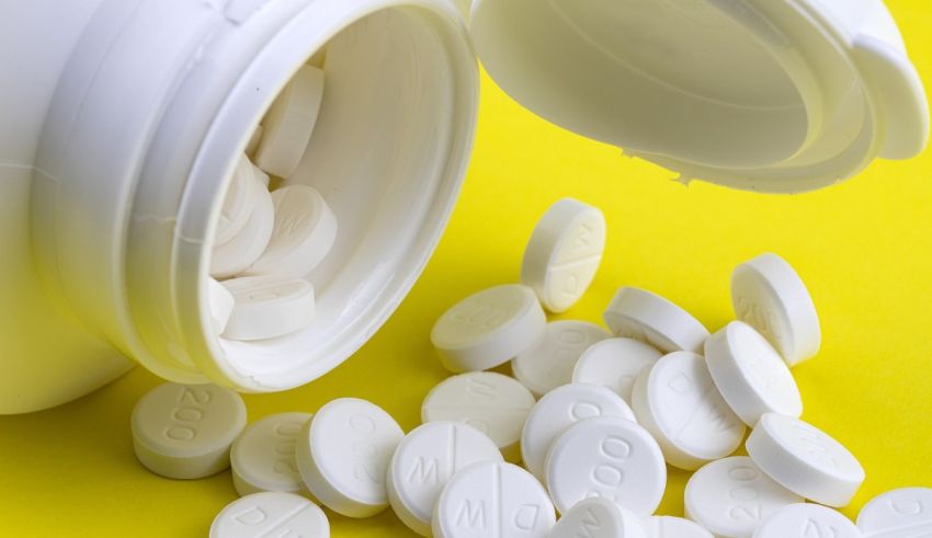 White pills spilling out of a bottle on a yellow background.