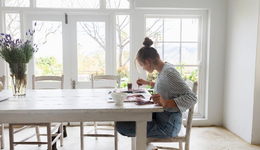 A woman sitting at a white table in a kitchen.
