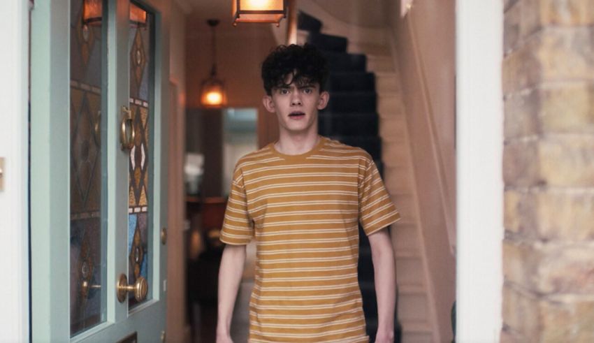 A young man in a yellow striped shirt standing in front of a door.