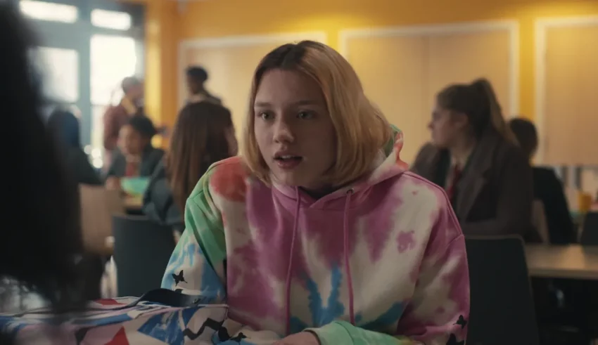 A girl in a tie dye hoodie sitting at a table.