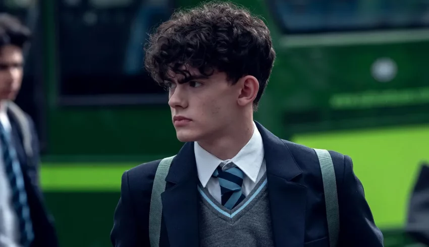 A young man in a school uniform walking down the street.