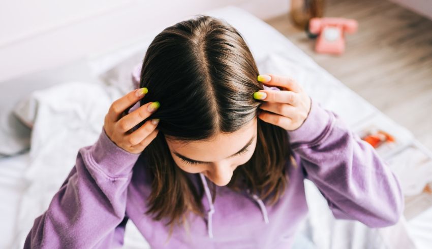 A woman is laying on a bed with her hands on her hair.