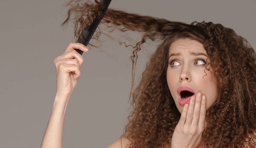 A woman is combing her curly hair with a comb.