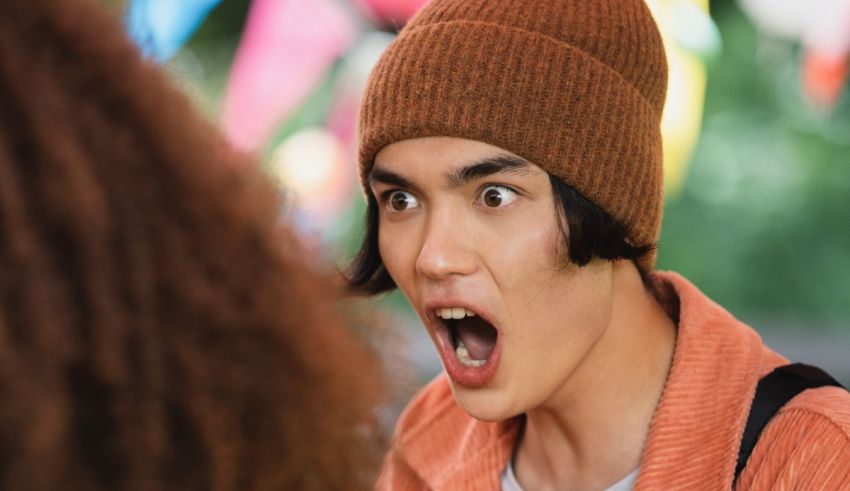 A young man with a beanie looking at his hair.