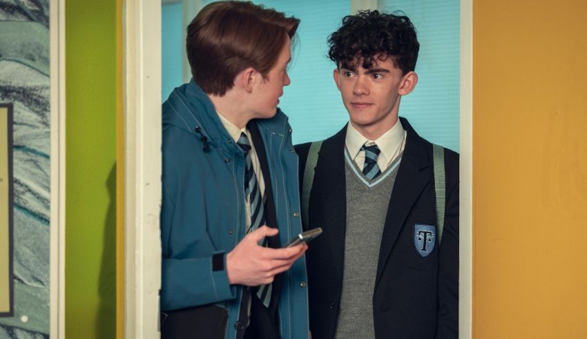 Two boys in school uniforms talking to each other.
