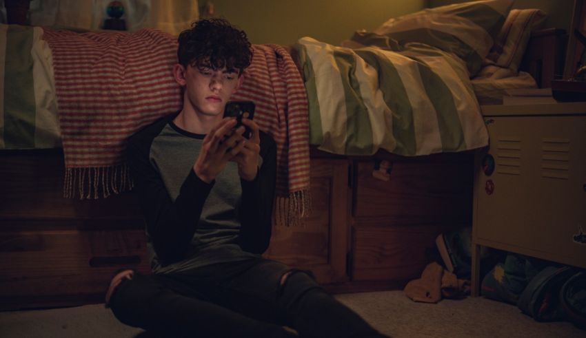 A young man sitting on the floor with a cell phone.