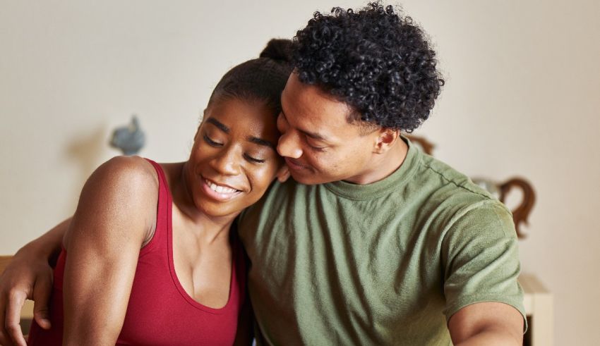 A man and woman hugging while sitting on a couch.
