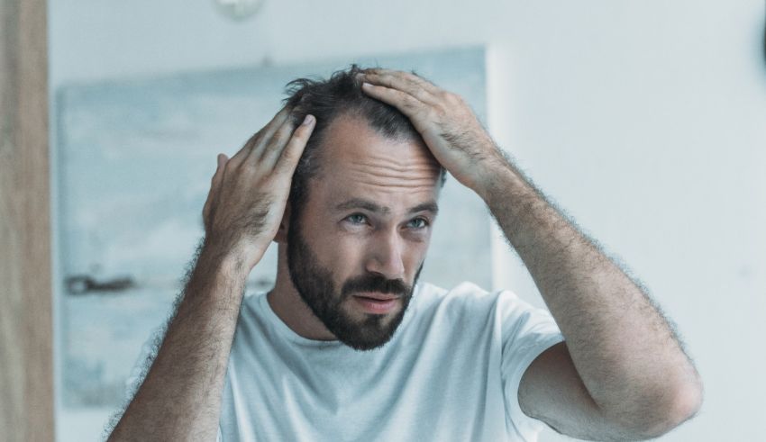 A man holding his hair in front of a mirror.